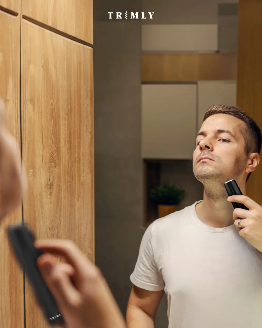 Man trimt zijn baard met de Trimly trimmer, zichtbaar haarresten tonen een strak resultaat.