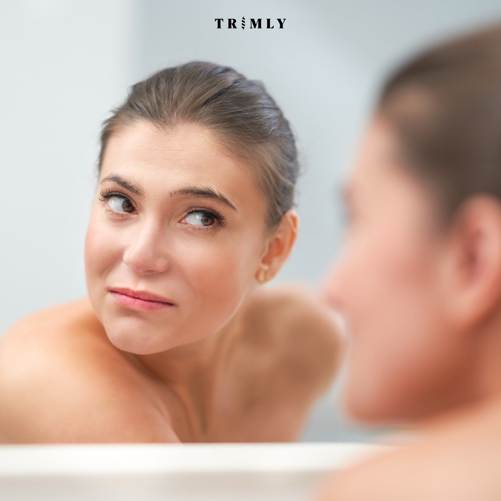 Vrouw kijkt onzeker naar haar wenkbrauwen zonder trimmer.