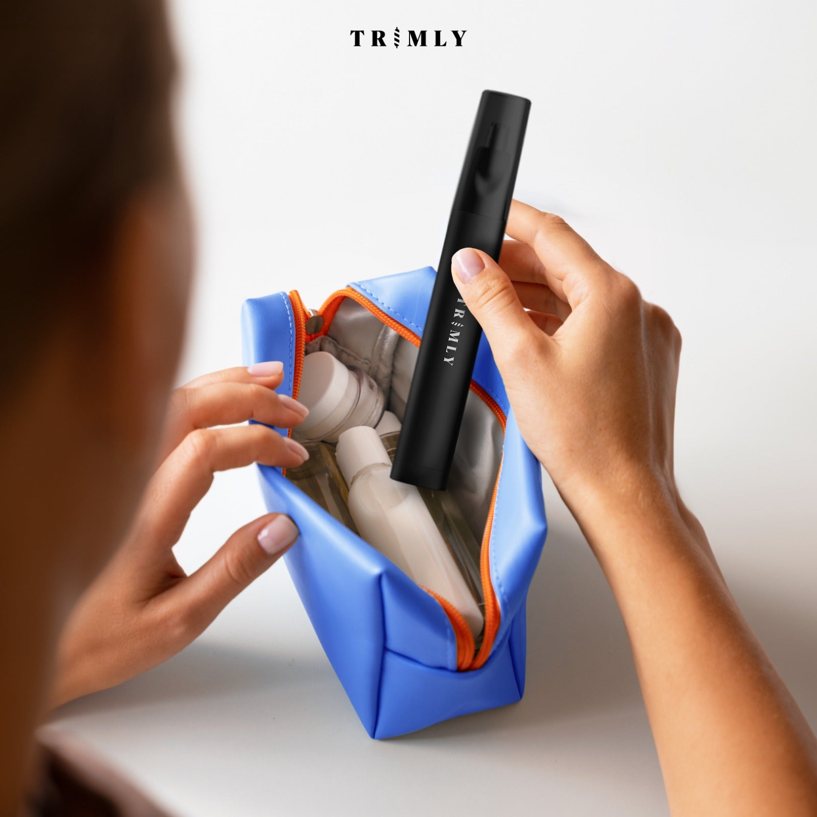 Vrouw pakt de Trimly Precision Pro trimmer uit haar toilettas, perfect voor onderweg en op reis
